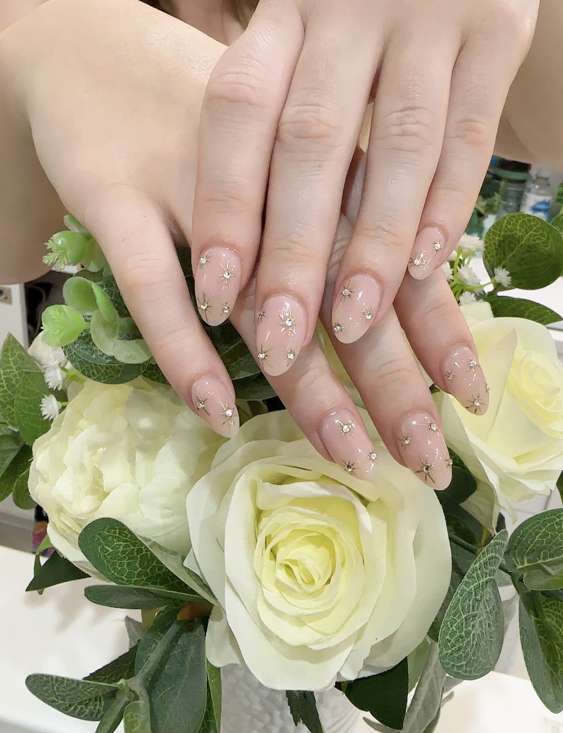 Nude almond nails set with fine gold stars and crystals